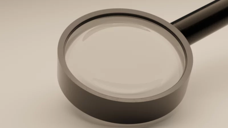 Loupe posée sur fond clair illustrant l’analyse, l’audit et la recherche dans un projet d’acquisition d’entreprise.