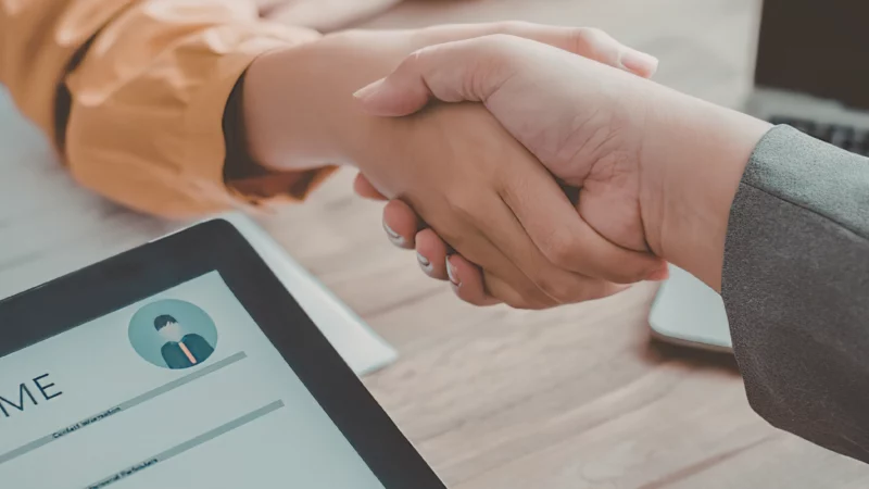 Poignée de main entre deux personnes symbolisant un accord de négociation dans le cadre d’une acquisition d’entreprise.