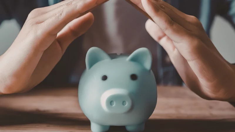 Tirelire protégée par des mains illustrant le financement et la sécurisation d’un projet d’acquisition d’entreprise.