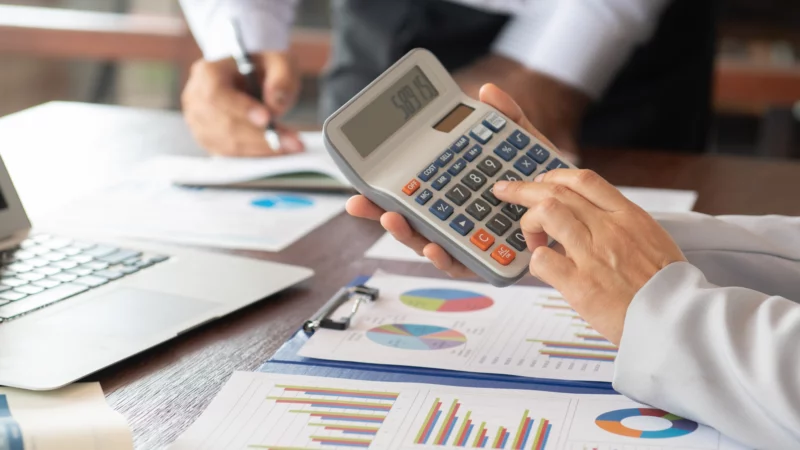 Calculatrice, graphiques financiers et documents de travail utilisés pour analyser une acquisition d’entreprise.